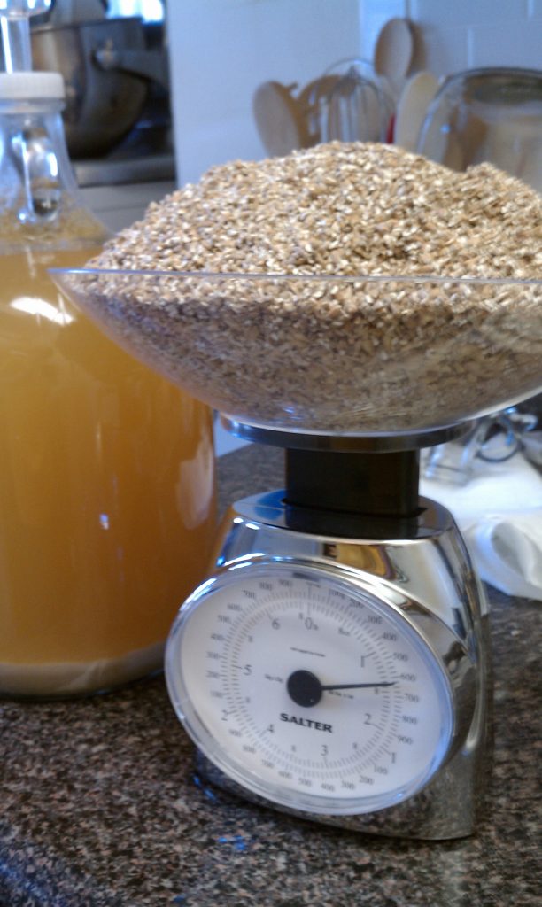 Grain on a scale with a fermented beer in the background